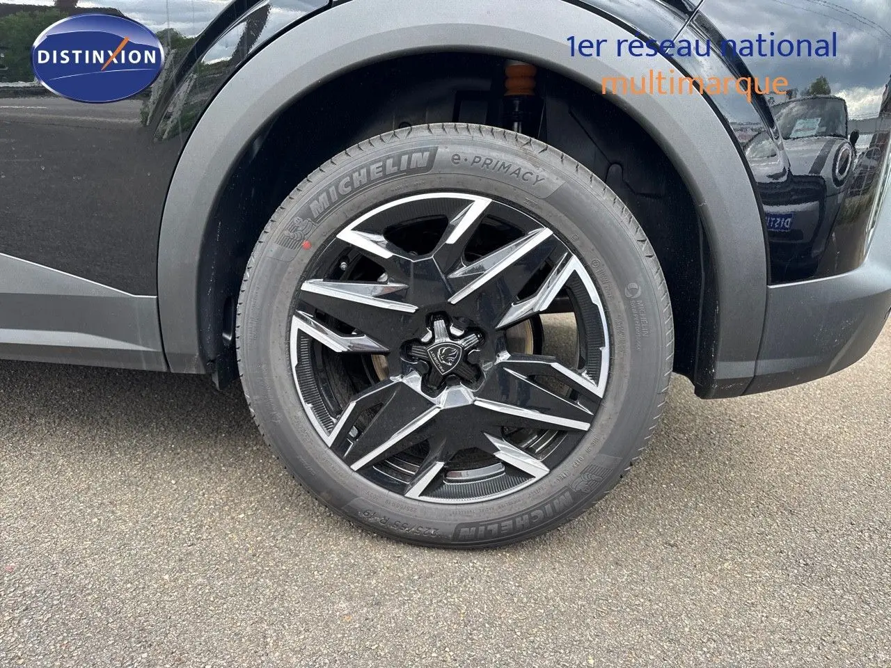 Gros plan sur la roue avant gauche du Peugeot 3008 Hybrid 2025 noir perle métal avec jante alliage noire et argentée design moderne.