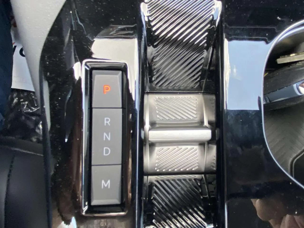 Gros plan sur la console centrale noire brillante de la Citroën C5 X 2023, avec sélecteur de boîte auto en mode parking.