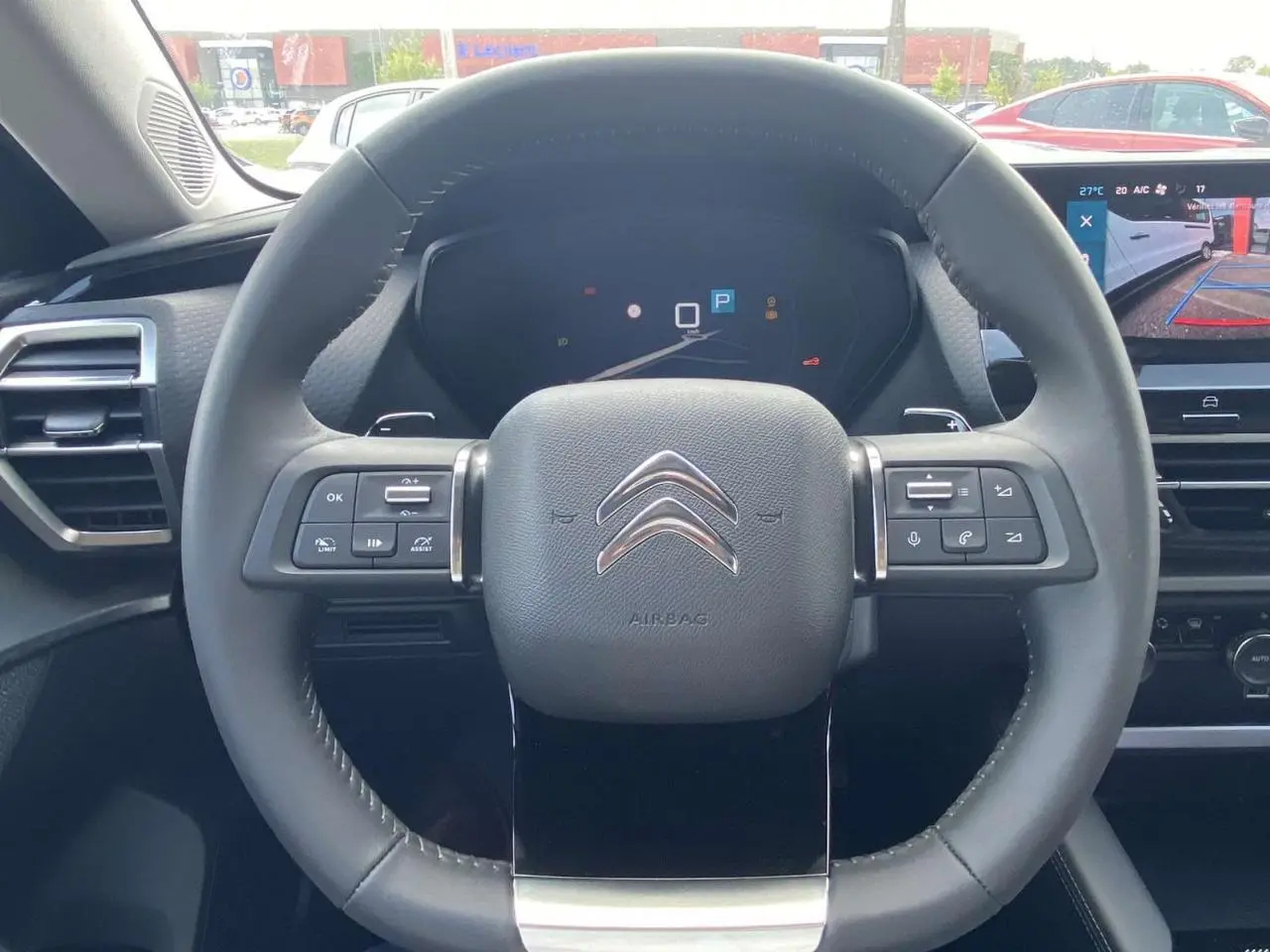 Vue centrée sur le volant cuir gris du Citroën C5 X 2023 avec tableau de bord numérique et écran tactile de recul.