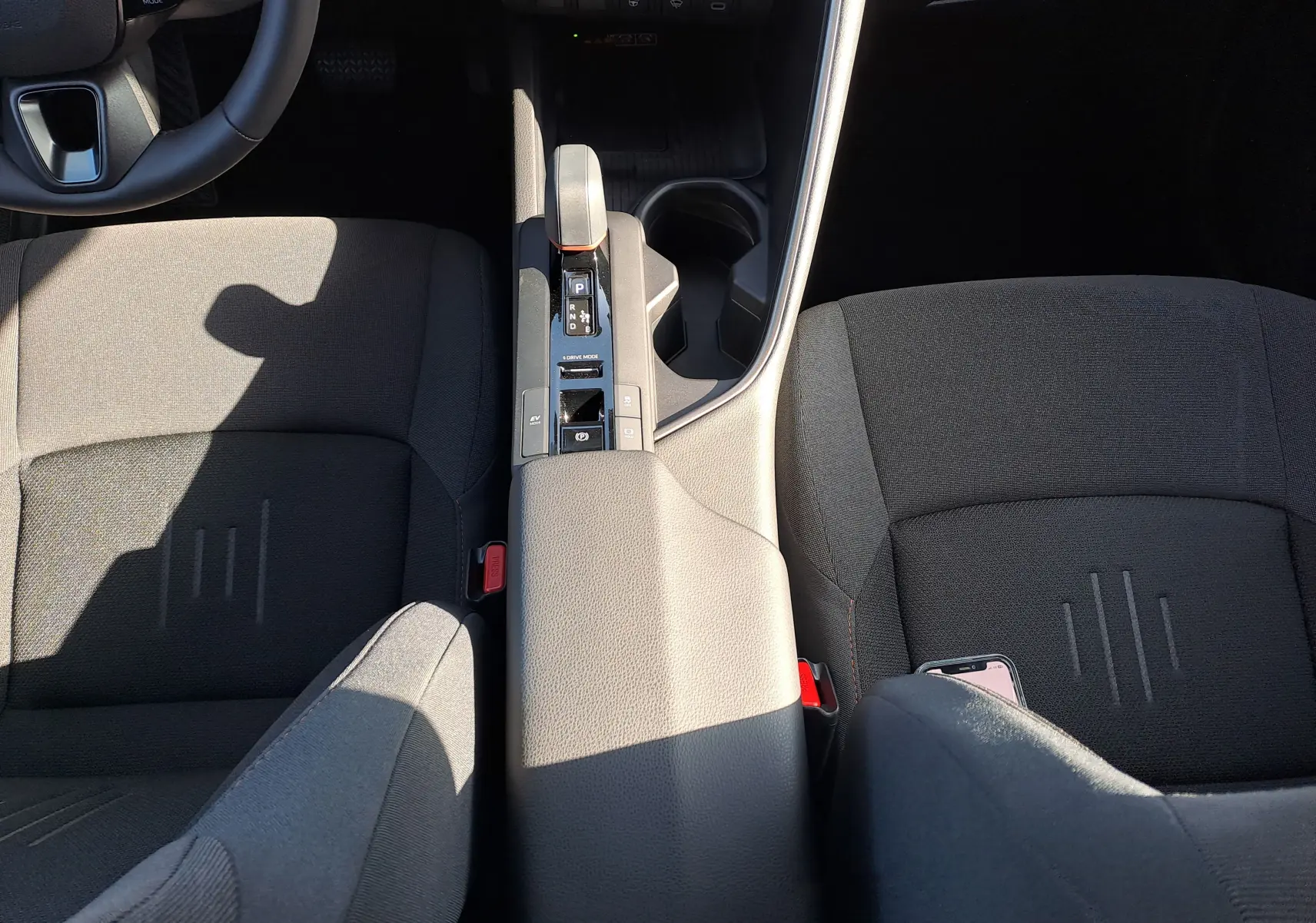 Vue intérieure centrée sur la console centrale du Toyota C-HR gris minéral, avec levier de vitesse et commandes climatisation.