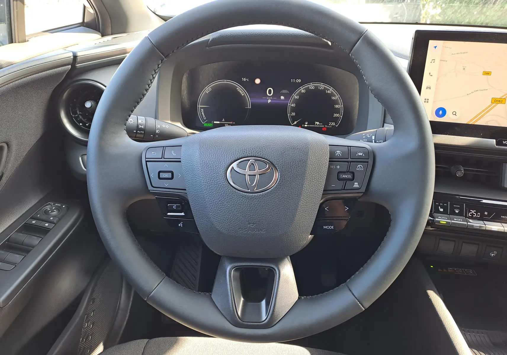 Vue rapprochée du volant et du tableau de bord numérique d'un Toyota C-HR gris minéral, version hybride 2025.