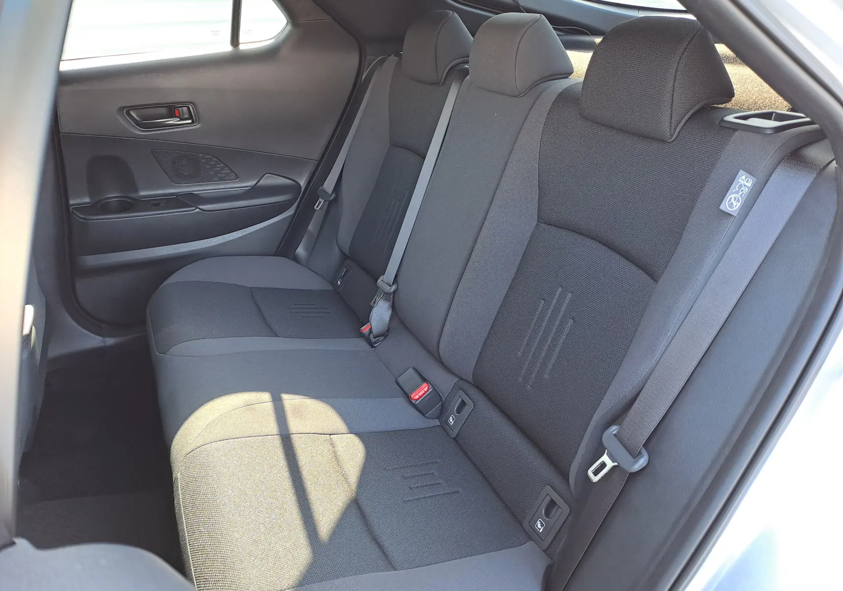 Vue rapprochée de la porte arrière droite grise minéral du Toyota C-HR 2025, avec poignée intérieure et porte-gobelet intégré.