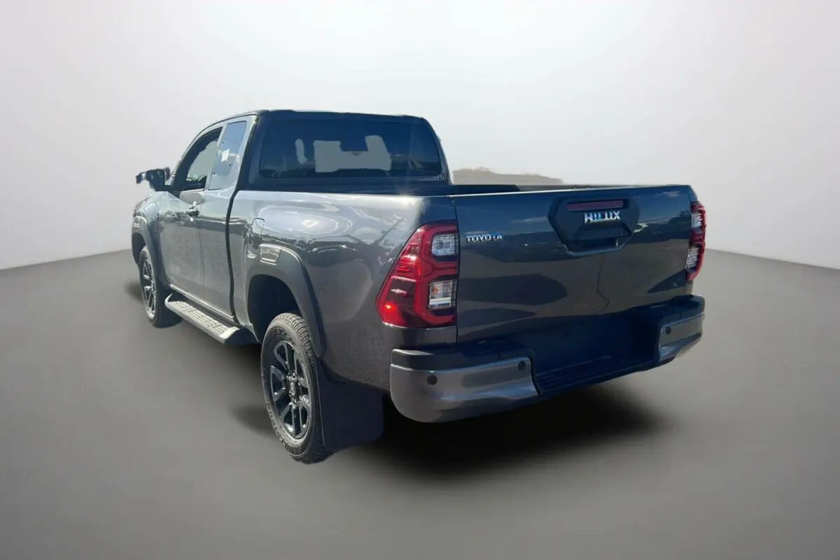 Toyota Hilux 4x4 gris atlas 2025 vu en 3/4 arrière droit, avec hayon et feux arrière distinctifs rouges.