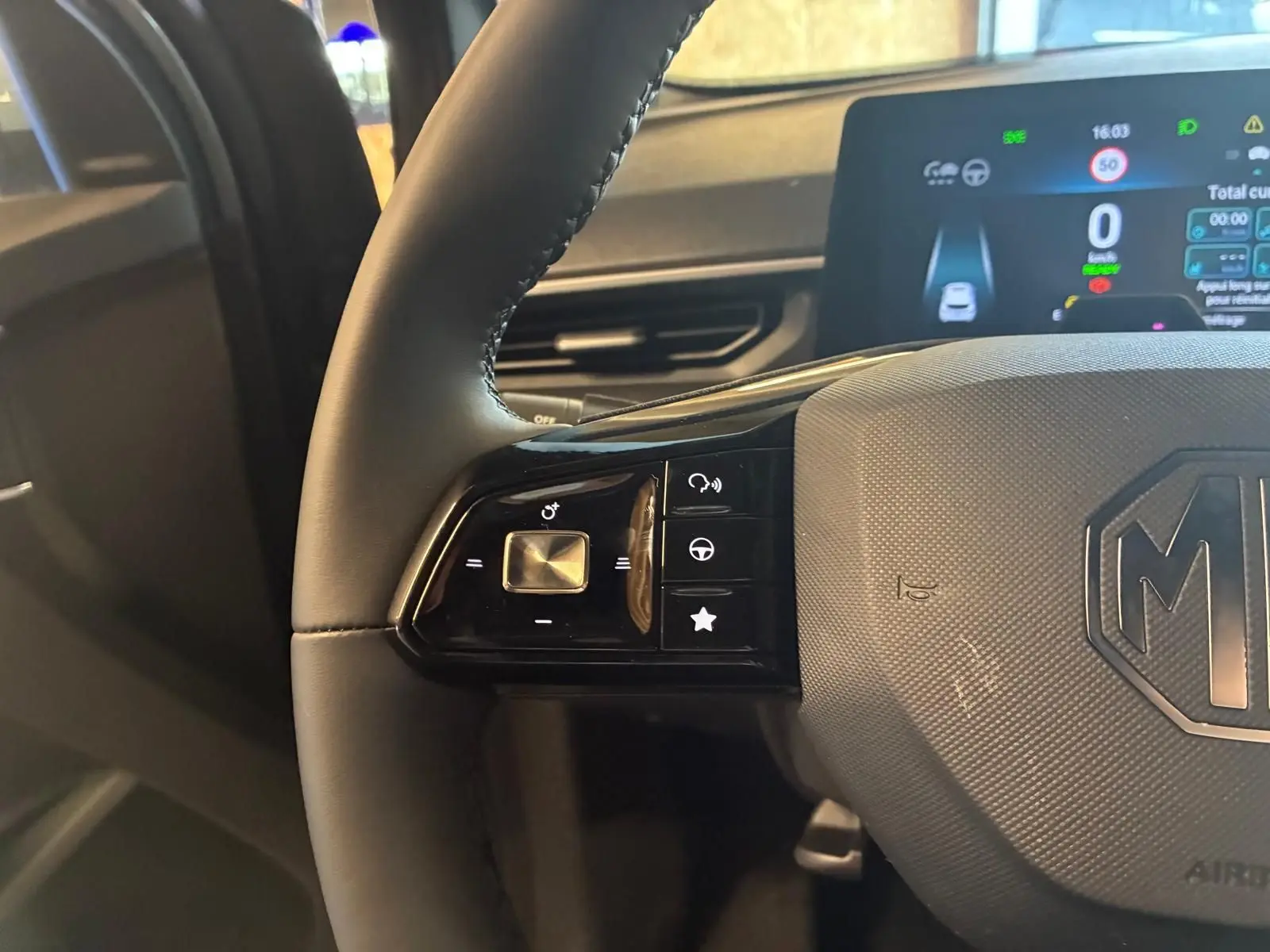 Gros plan sur le volant noir du MG3 1.5 HYBRID+ 195 LUXURY avec commandes intégrées et tableau de bord numérique visible.