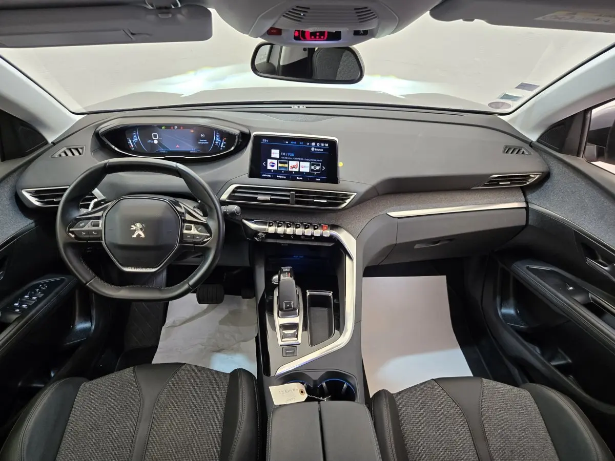 Vue intérieure avant du Peugeot 5008 gris clair, mettant en valeur le tableau de bord digital et l'écran tactile central.