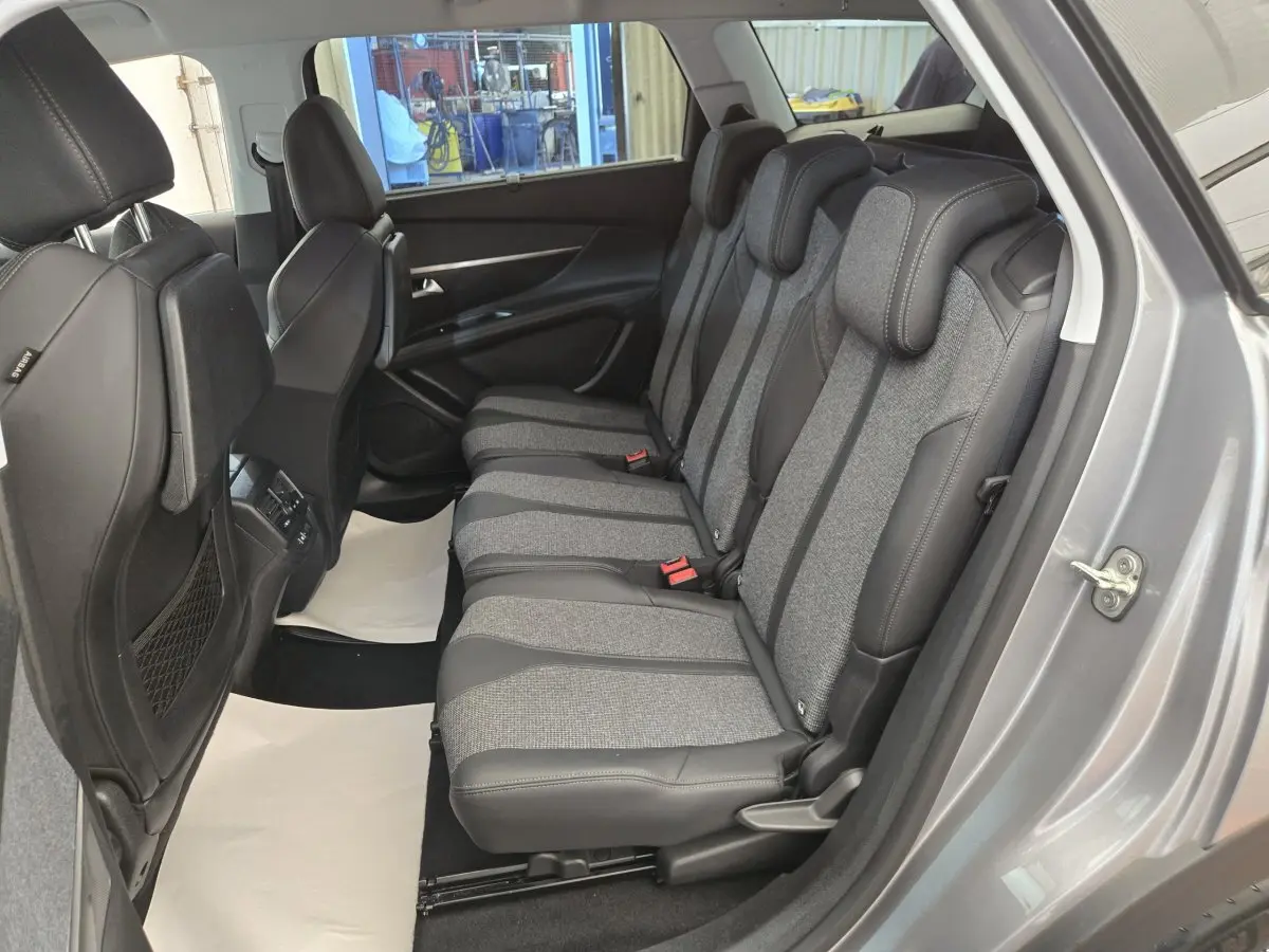 Vue latérale droite de l'intérieur du Peugeot 5008 gris clair, montrant la banquette arrière en tissu et cuir bicolore.