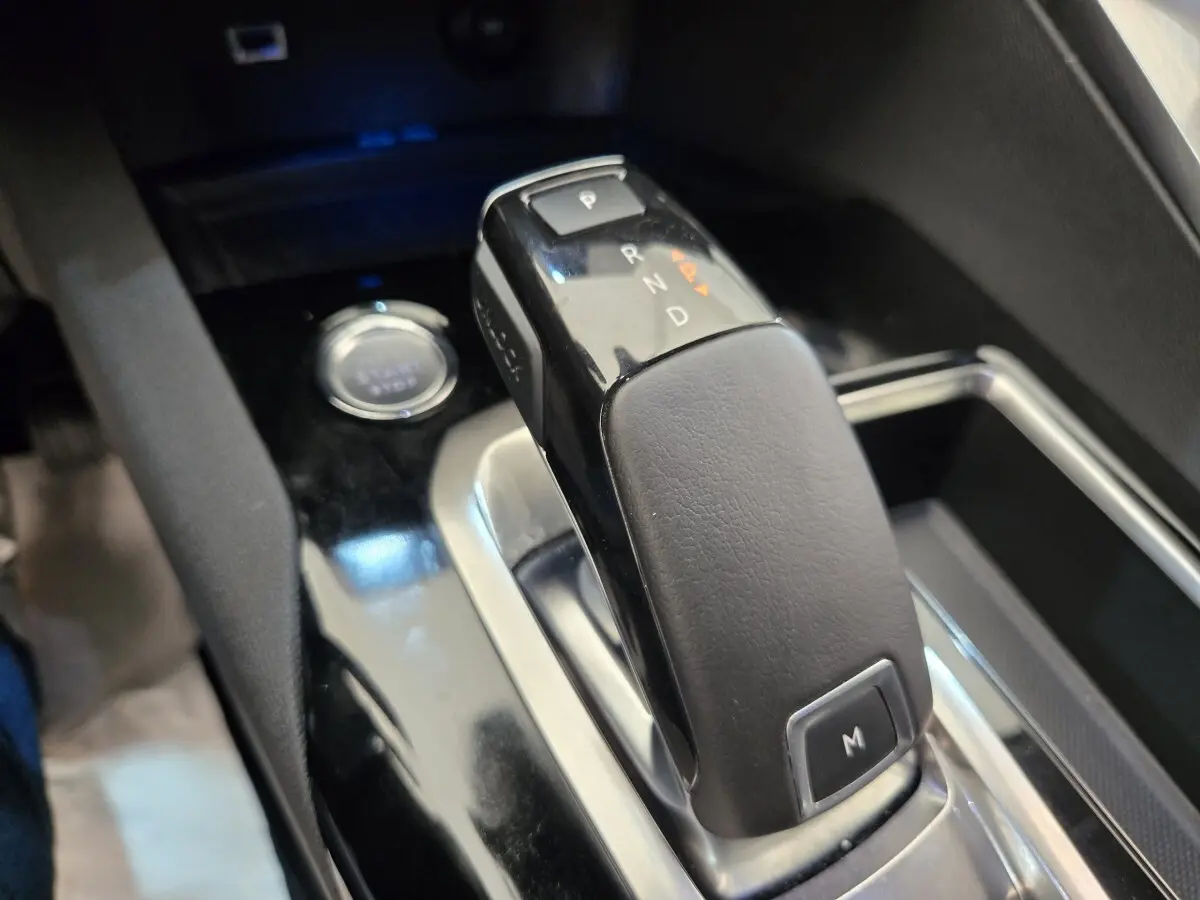 Gros plan sur la commande de boîte automatique noire du Peugeot 5008, avec bouton démarrage visible en arrière-plan.