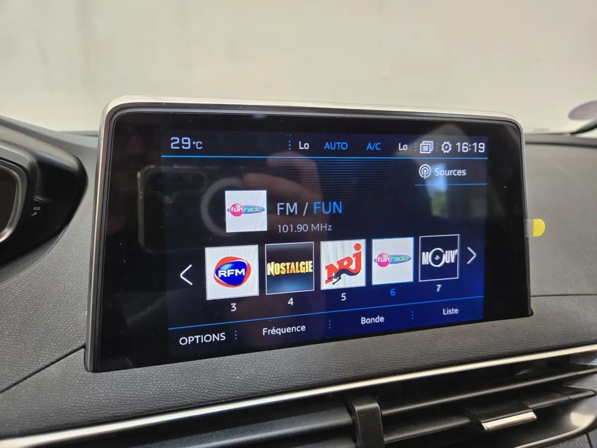 Écran tactile central du Peugeot 5008 gris clair affichant les stations radio FM avec interface moderne.