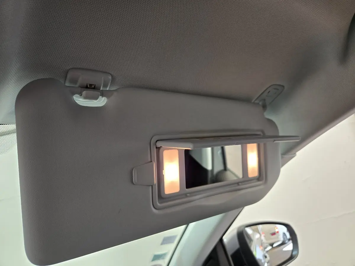 Miroir de courtoisie éclairé sur pare-soleil côté conducteur dans Peugeot 5008 gris clair, vue intérieure rapprochée.