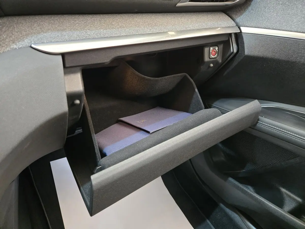 Gant de boîte à gants ouvert côté passager dans l’habitacle noir du Peugeot 5008 gris clair, avec livret à l’intérieur.