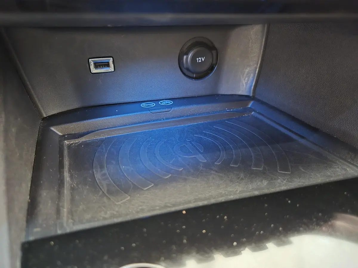 Gros plan sur la console centrale du Peugeot 5008 gris clair, montrant prise USB, prise 12V et zone de charge sans fil.