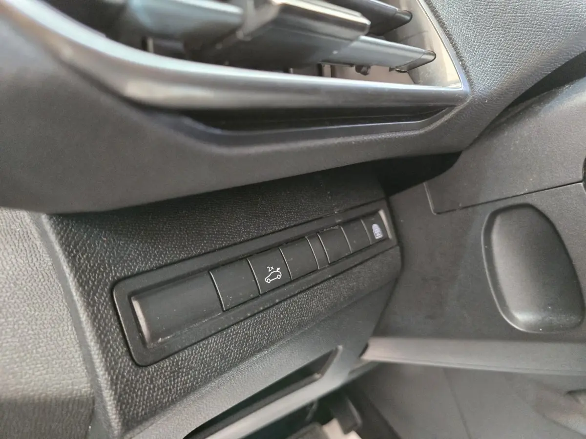 Détail intérieur côté gauche montrant les commandes d'ouverture du coffre et de verrouillage sur Peugeot 5008 gris clair.