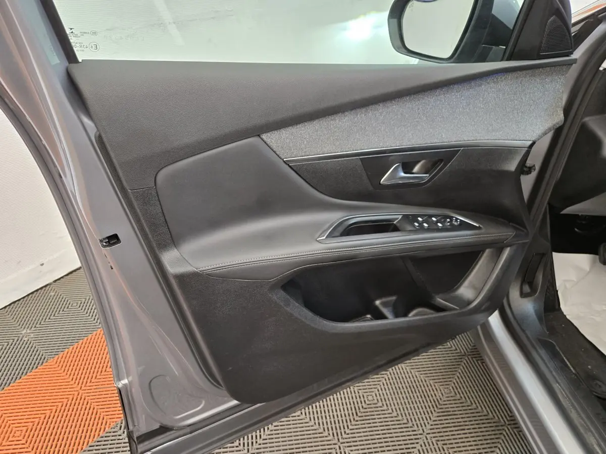 Vue intérieure de la porte avant gauche grise du Peugeot 5008 avec commandes de vitres et poignée métallique.