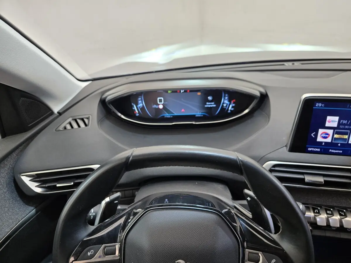 Vue intérieure centrée sur le volant cuir et le tableau de bord digital du Peugeot 5008 gris clair, version 2020.