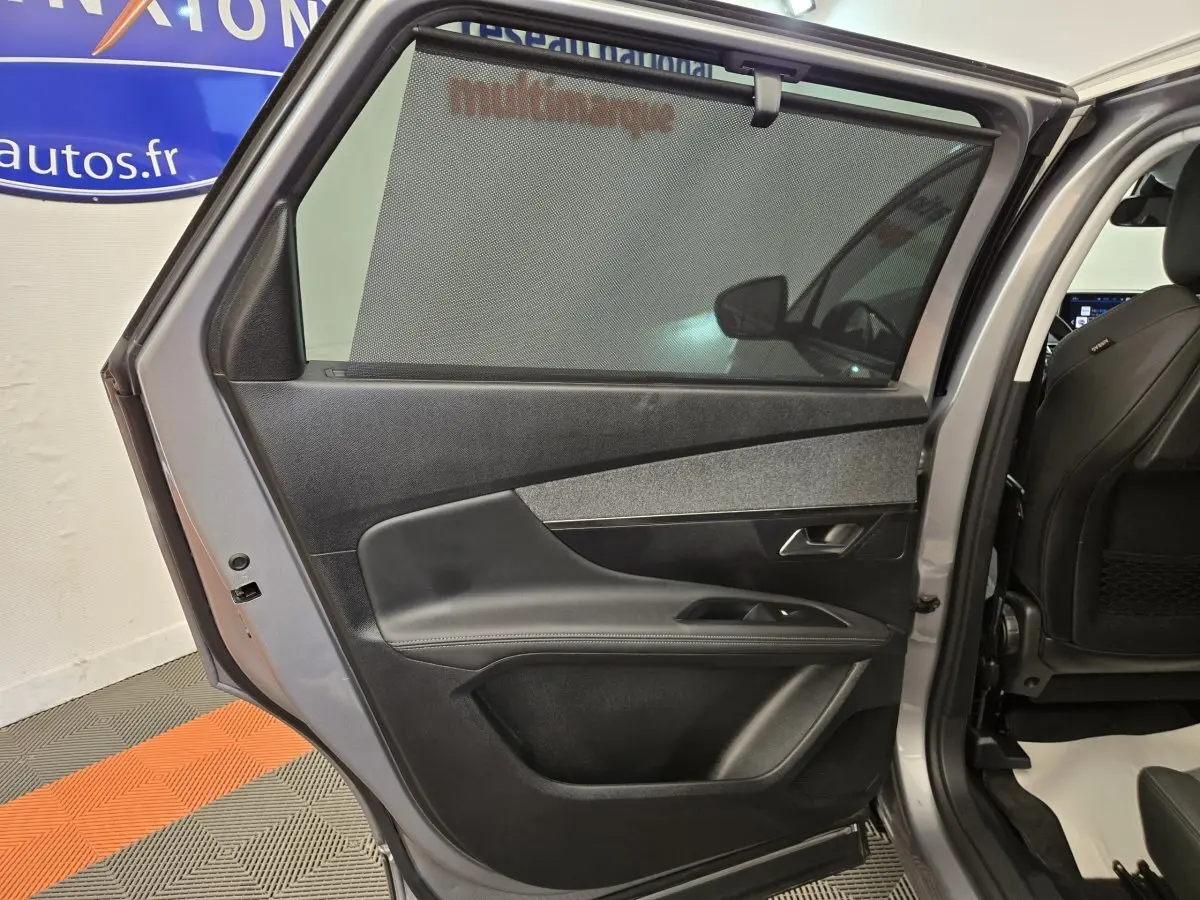 Vue intérieure de la porte arrière droite gris clair du Peugeot 5008 avec store pare-soleil et garniture noire.