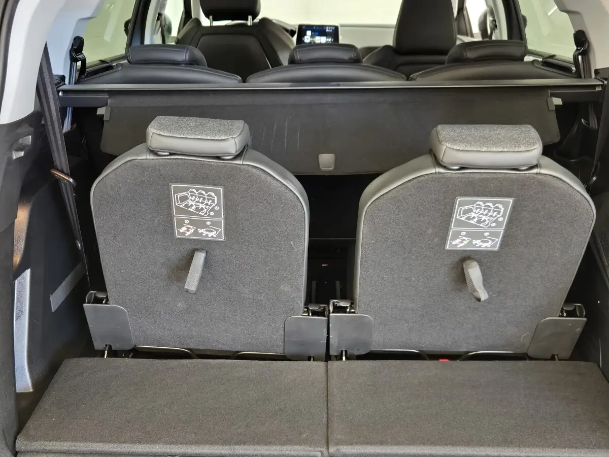 Vue arrière intérieure du coffre du Peugeot 5008 gris clair avec sièges arrière rabattus et tablette de coffre visible.