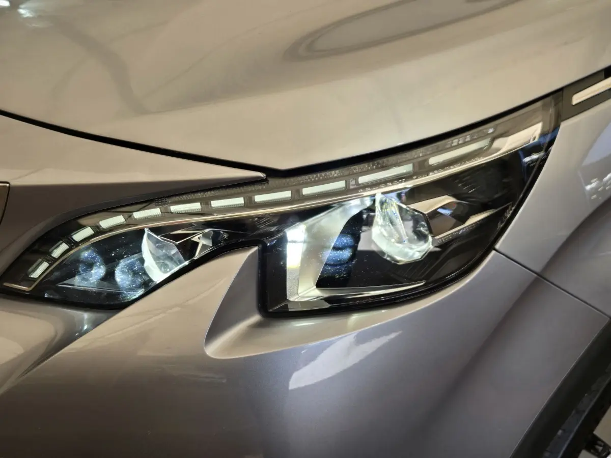 Gros plan sur le phare avant droit du Peugeot 5008 gris clair, mettant en valeur ses LED distinctives et lignes modernes.