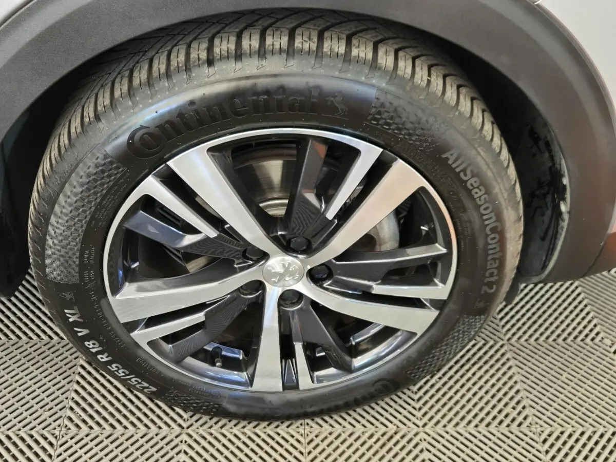 Gros plan sur la roue avant droite du Peugeot 5008 gris clair, avec jante alliage bicolore et pneu Continental.