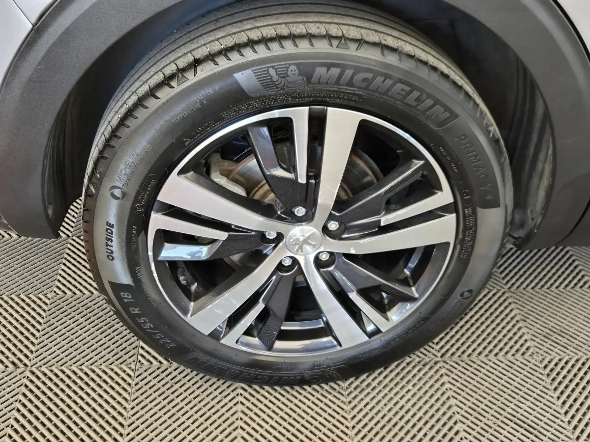 Gros plan sur la roue avant droite du Peugeot 5008 gris clair, avec jante alliage bicolore et pneu Michelin.