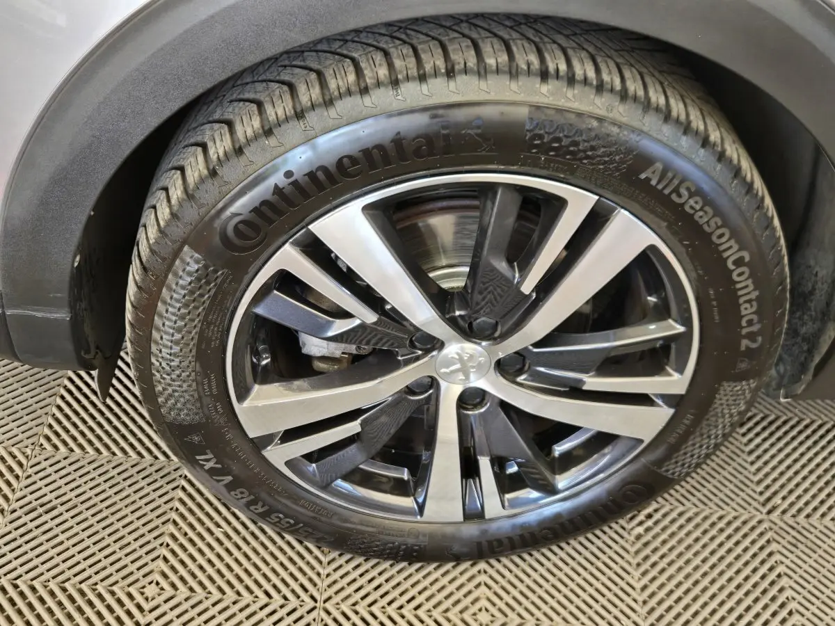 Gros plan sur la roue avant droite du Peugeot 5008 gris clair avec jante alliage et pneu Continental AllSeasonContact 2.