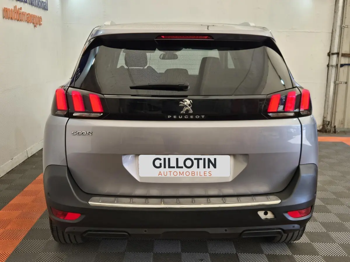 Vue arrière d'un Peugeot 5008 gris clair avec feux arrière LED caractéristiques et logo au centre du hayon.