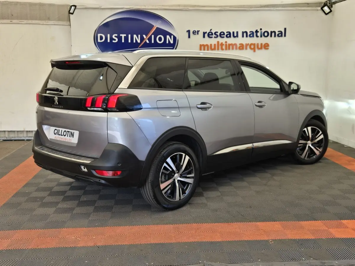 Peugeot 5008 gris clair vue 3/4 arrière droit, avec feux arrière LED et jantes alliage bicolores.