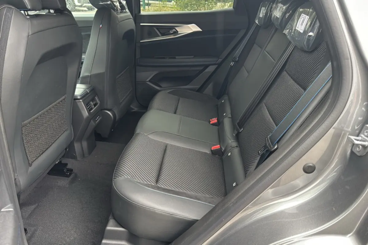 Vue intérieure arrière côté droit du Renault Austral ETECH 200 Esprit Alpine Plus 2025, sièges noirs avec surpiqûres bleues.