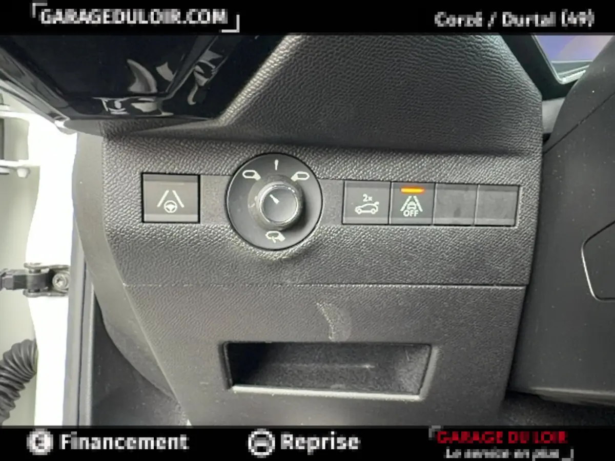 Gros plan sur les commandes noires du tableau de bord côté gauche du DS7 Crossback blanc, avec bouton d'ouverture coffre et régulateur.