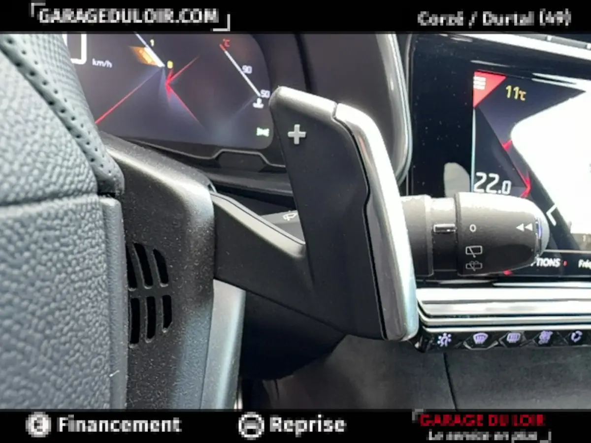 Gros plan sur la palette de changement de vitesse côté droit du volant noir du DS7 Crossback blanc, avec tableau de bord numérique.