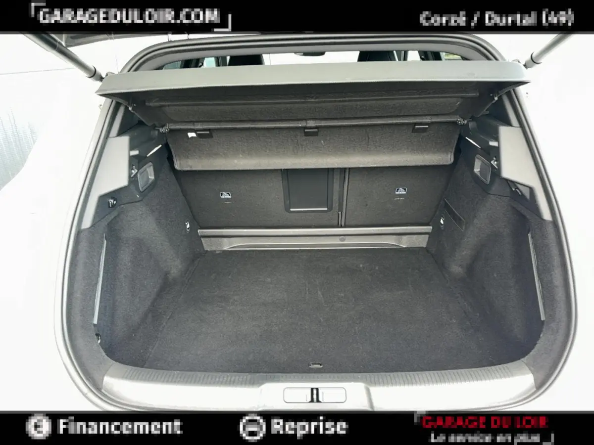 Coffre ouvert vu de l'arrière d'un DS7 Crossback blanc, espace de chargement vide et tapis noir.