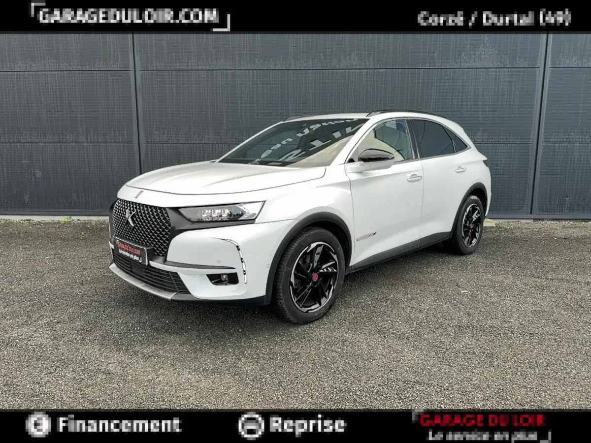 DS7 Crossback blanc en 3/4 avant droit, avec calandre noire distinctive et jantes noires brillantes.