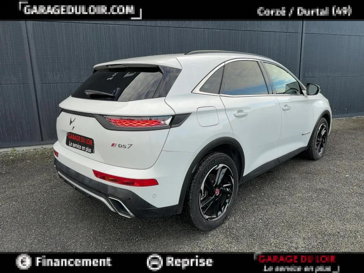 Vue 3/4 arrière droite d'un DS7 Crossback blanc avec jantes noires et feux arrière LED distinctifs.