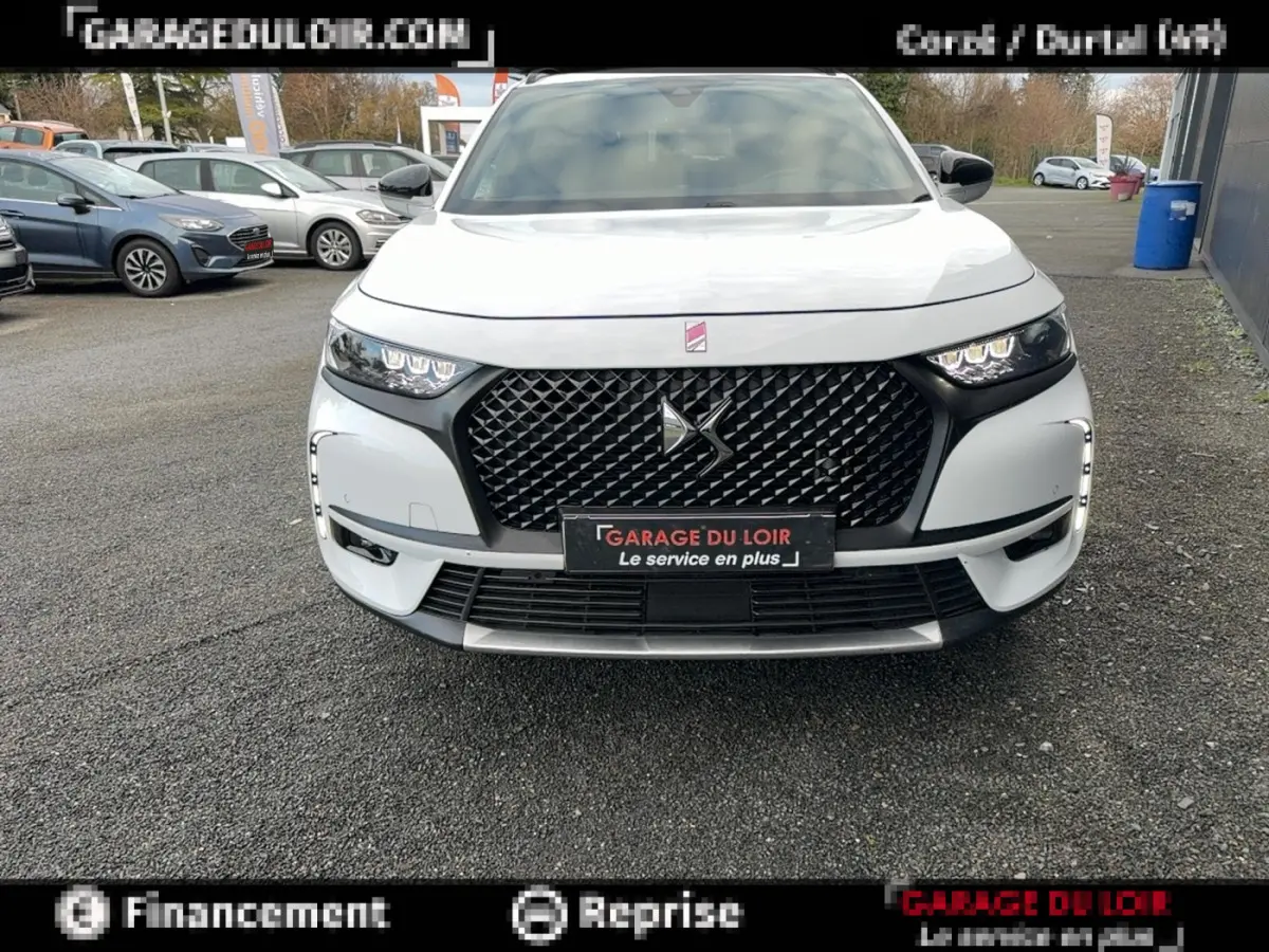 Vue avant frontale du DS7 Crossback blanc avec sa calandre noire distinctive et ses phares LED allumés.