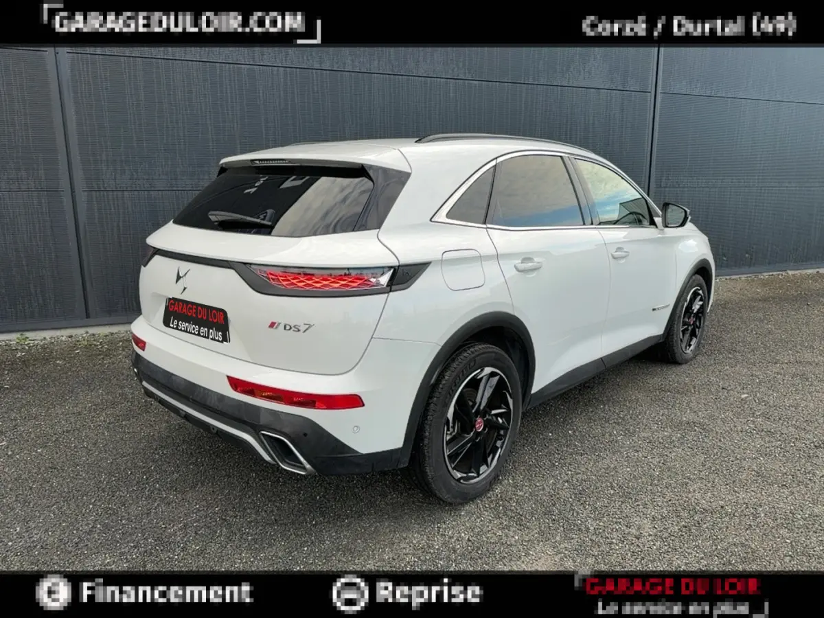 Vue 3/4 arrière droite d'un DS7 Crossback blanc avec jantes noires et feux arrière LED distinctifs.