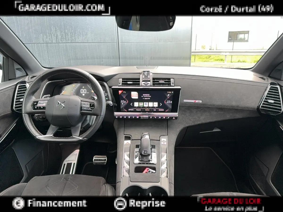 Vue intérieure avant du tableau de bord noir et volant cuir du DS7 Crossback blanc, avec écran tactile central allumé.