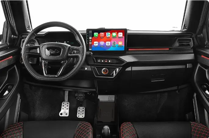 Vue frontale de l’habitacle noir et rouge de la Ligier JS50 0.5 REVO D+ Ultimate avec écran tactile central lumineux.