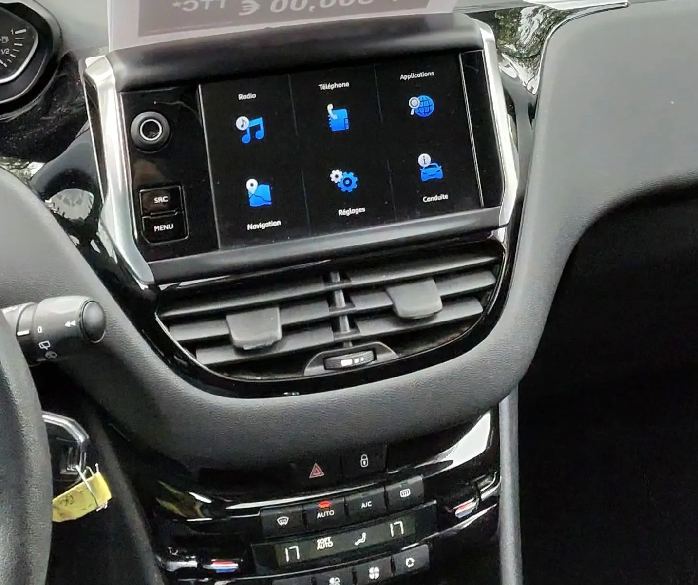 Vue intérieure du tableau de bord de la Peugeot 208 gris foncé, avec écran tactile et levier de vitesse manuel visible.