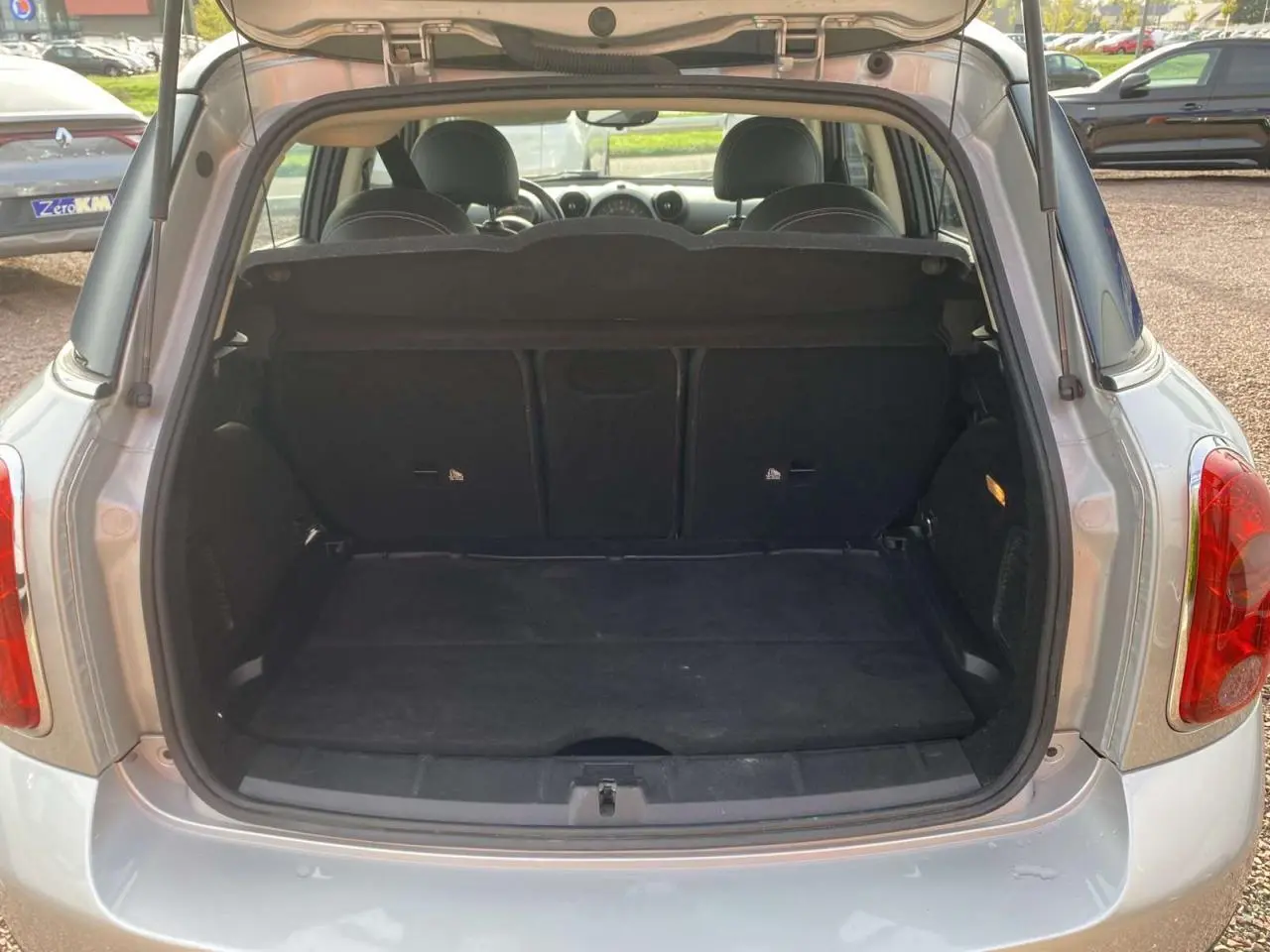 Coffre ouvert d'une MINI Countryman gris clair vue de l'arrière, montrant l'espace de chargement et l'intérieur des sièges arrière.