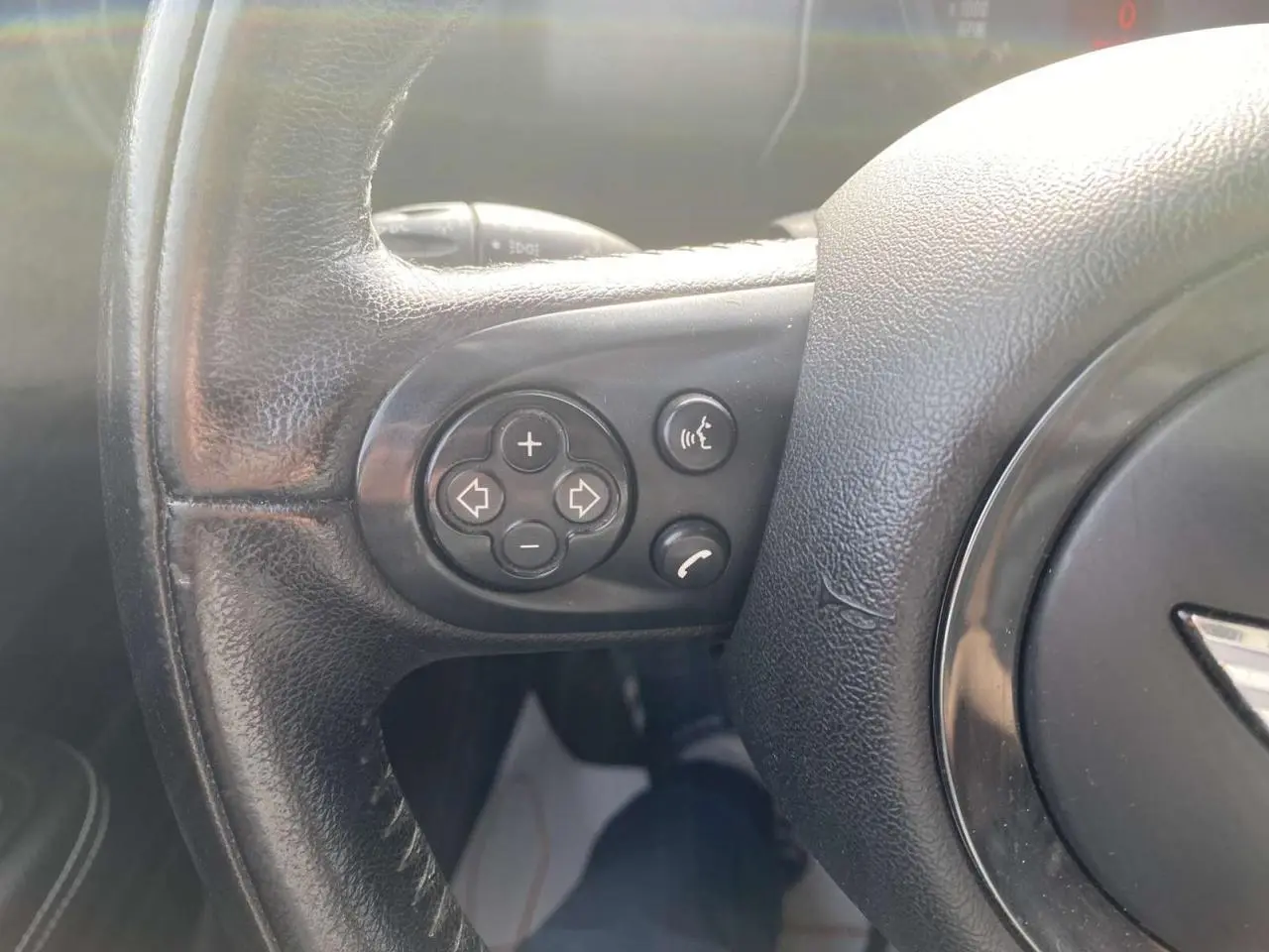 Gros plan sur les commandes vocales et téléphone intégrées au volant en cuir noir du MINI Countryman gris clair.