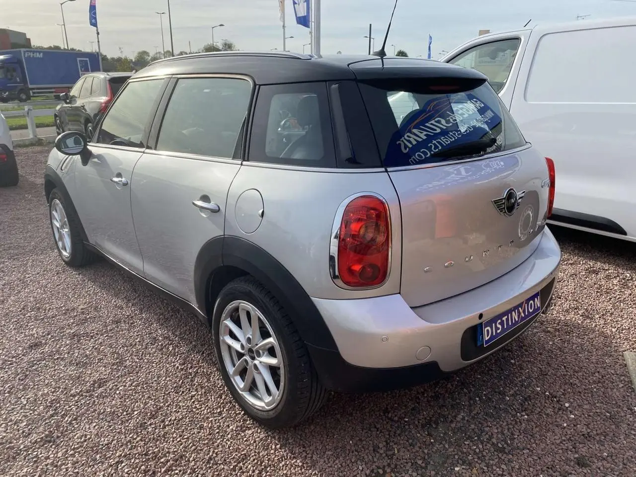Vue 3/4 arrière droite d'une MINI Countryman gris clair avec toit noir et feux arrière rouges.
