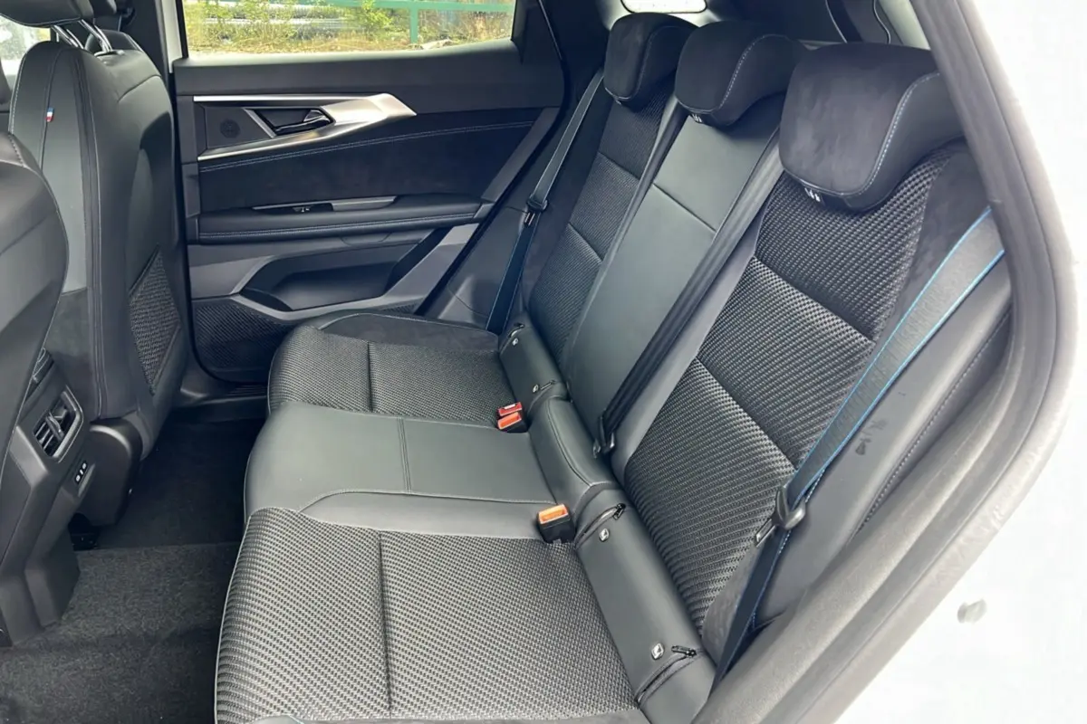 Intérieur arrière du Renault Austral E-Tech 200 Esprit Alpine Plus 2025, sièges noirs avec surpiqûres bleues visibles côté droit.