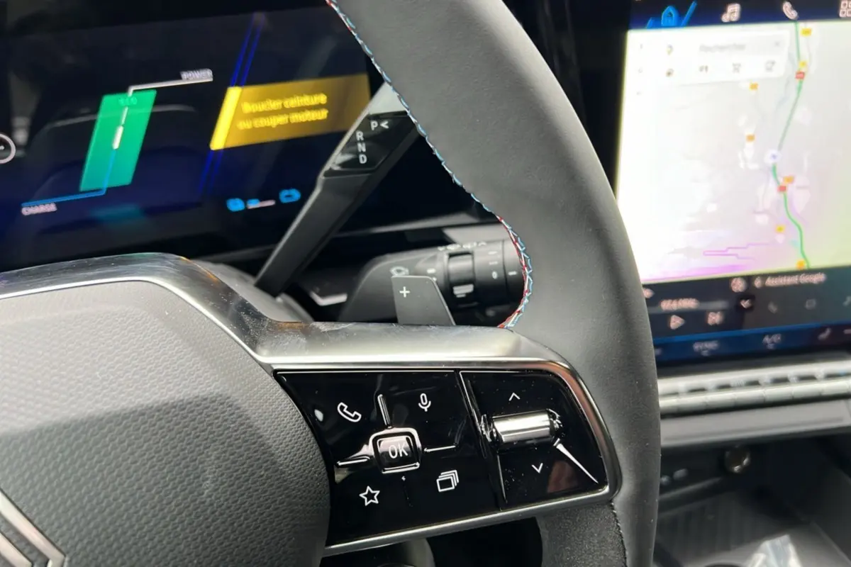 Gros plan sur la partie gauche du volant du Renault Austral E-Tech 200 Esprit Alpine Plus avec coutures tricolores et écran digital.