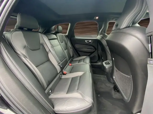 Vue intérieure arrière côté droit du Volvo XC60 noir 2021, sièges cuir noirs avec surpiqûres contrastées et toit panoramique.