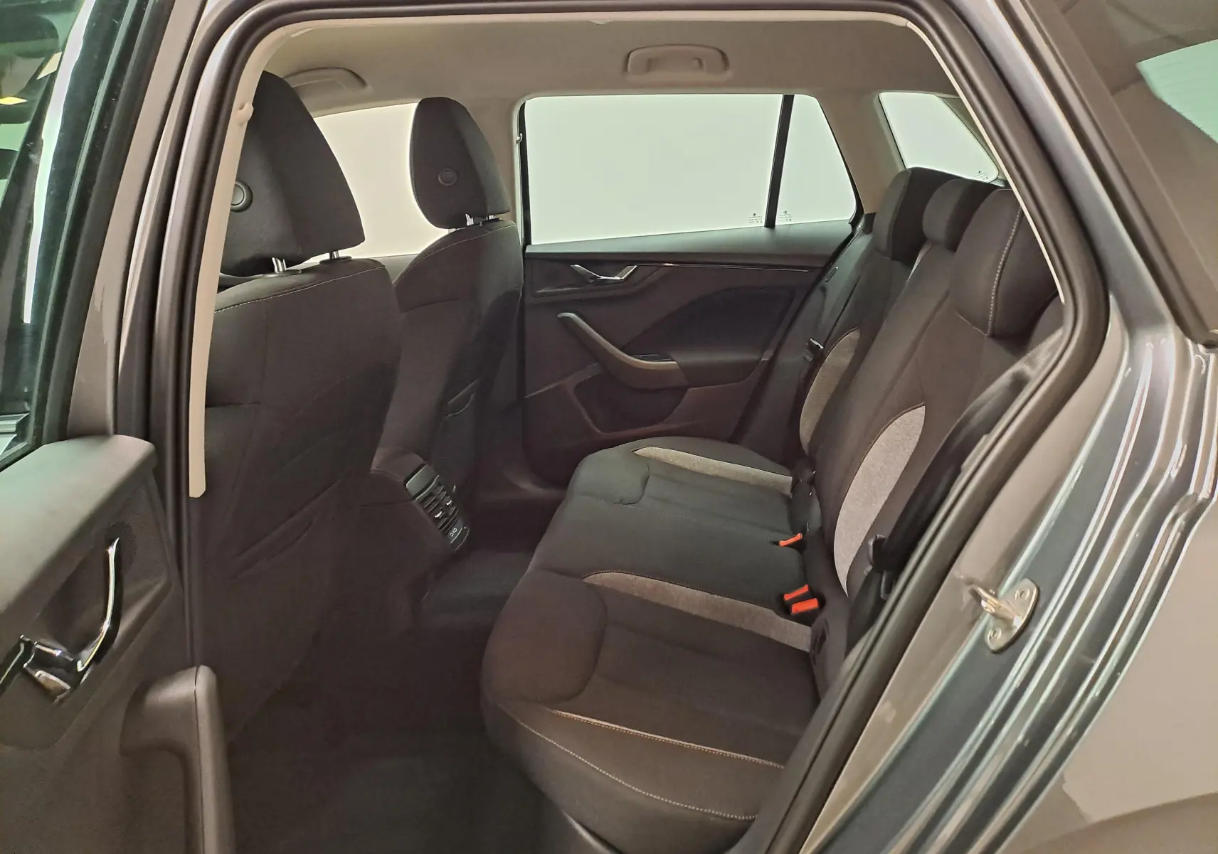 Vue intérieure arrière côté gauche du Skoda Kamiq gris graphite, montrant les sièges arrière en tissu bi-ton.