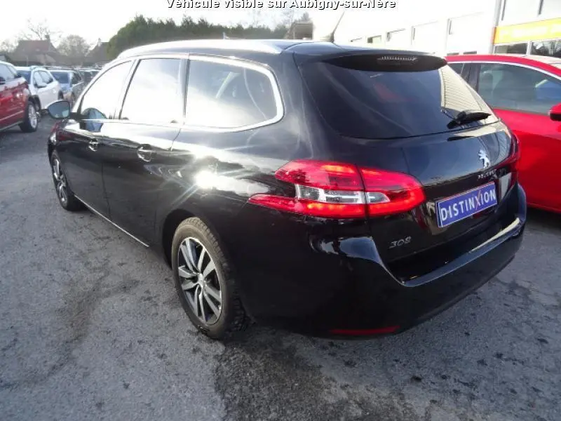 Peugeot 308 SW noire vue en 3/4 arrière droit, avec feux arrière allumés et jantes alliage visibles.