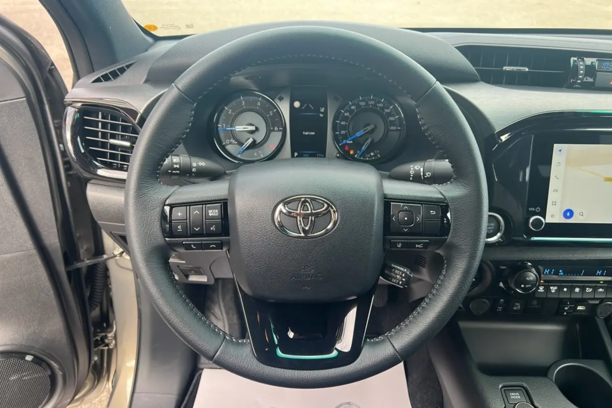 Vue intérieure centrée sur le volant noir du Toyota Hilux 4x4 2025, avec tableau de bord et écran tactile visibles.