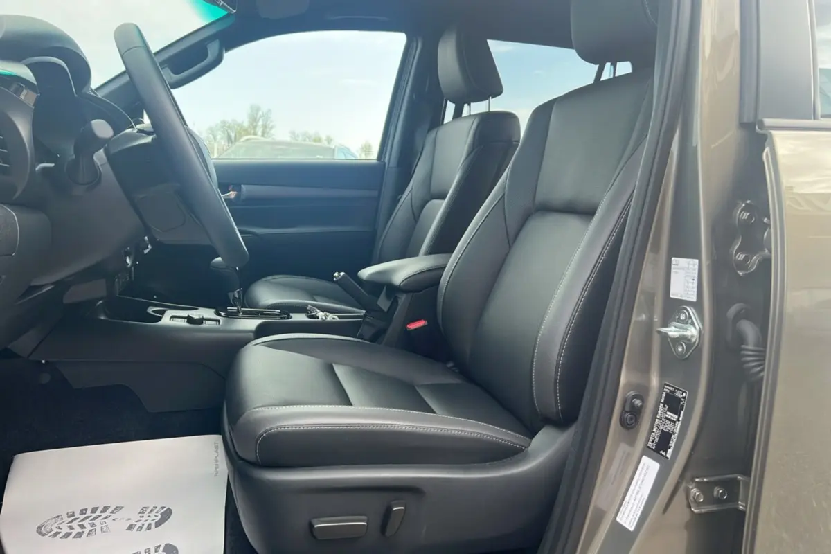 Intérieur côté conducteur du Toyota Hilux 2025 en bronze impérial, sièges cuir noirs et boîte automatique visible.
