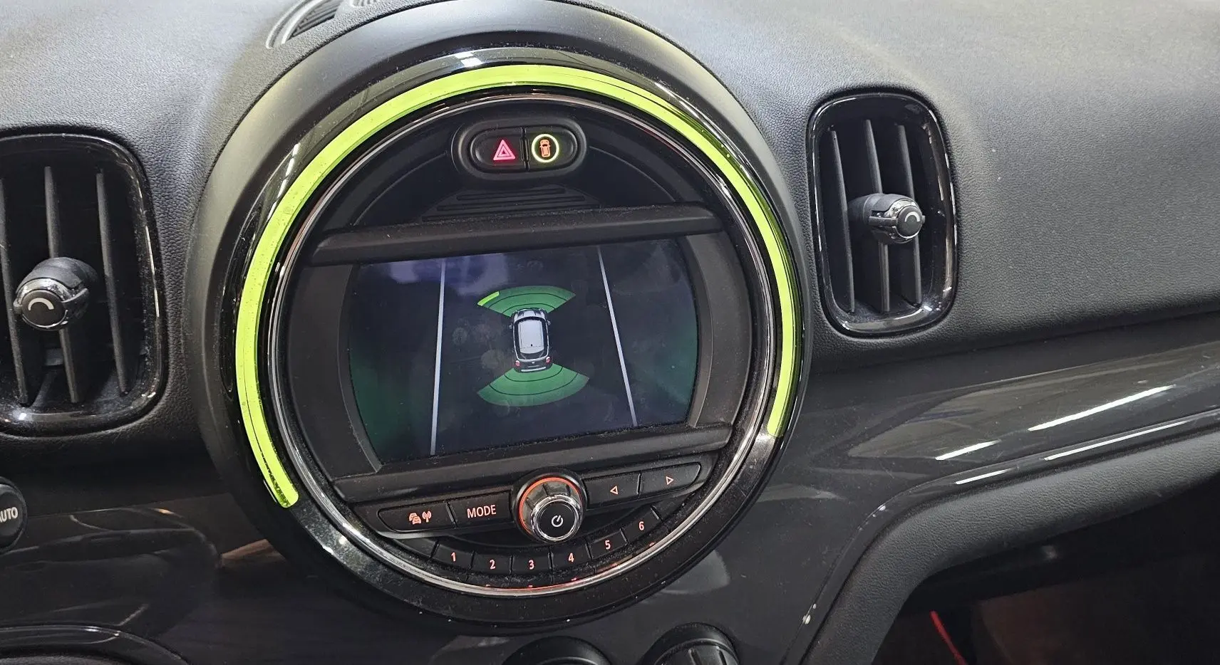 Vue rapprochée du tableau de bord du MINI Cooper Countryman 2018, avec écran central rond et éclairage vert autour.
