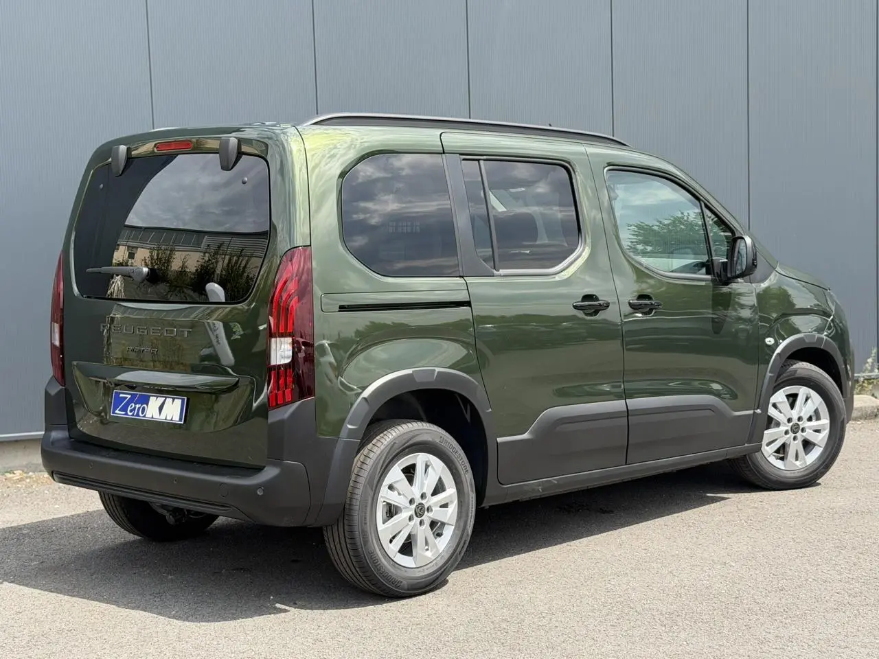 Vue 3/4 arrière droite du Peugeot Rifter 2026 vert Sirkka avec portes coulissantes et vitres arrière surteintées.