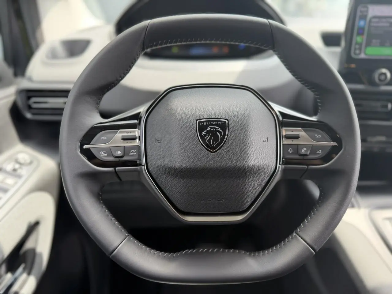 Vue rapprochée du volant cuir multifonction noir du Peugeot Rifter 2026, avec commandes intégrées et logo central lion.